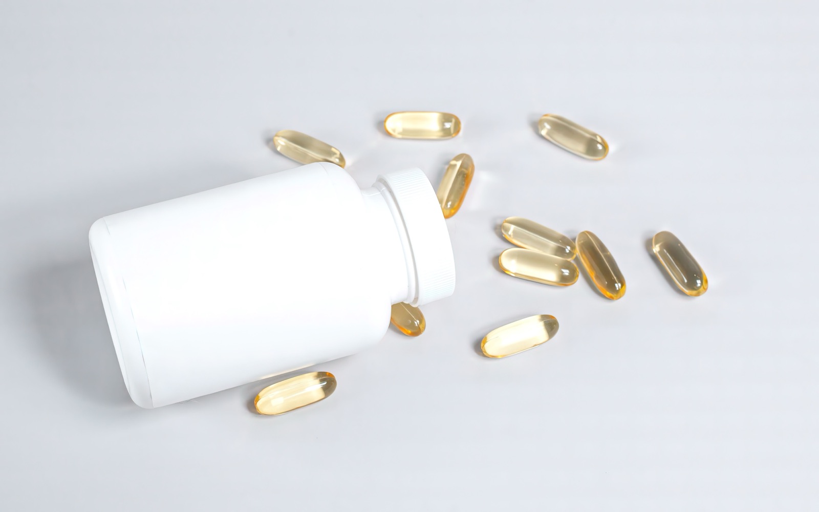 Softgel capsules spilling from a production bottle