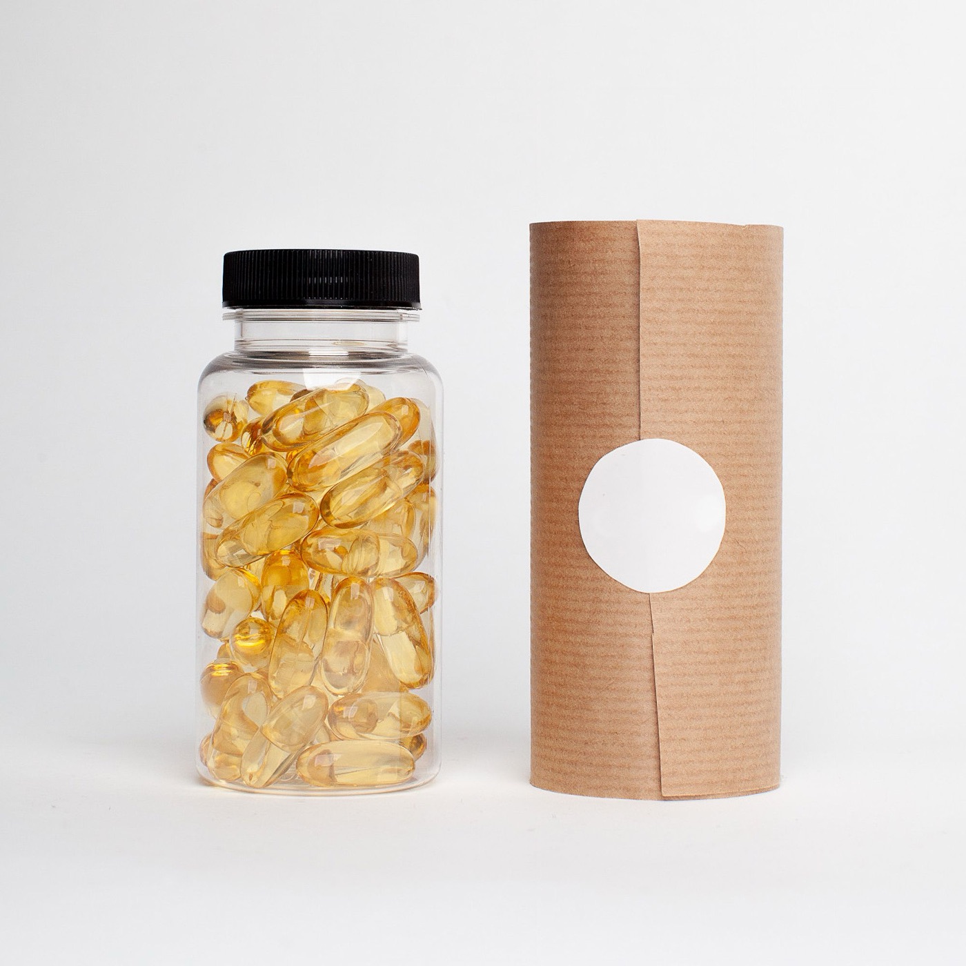 Softgel capsules in a client-branded bottle beside kraft-paper tube packaging